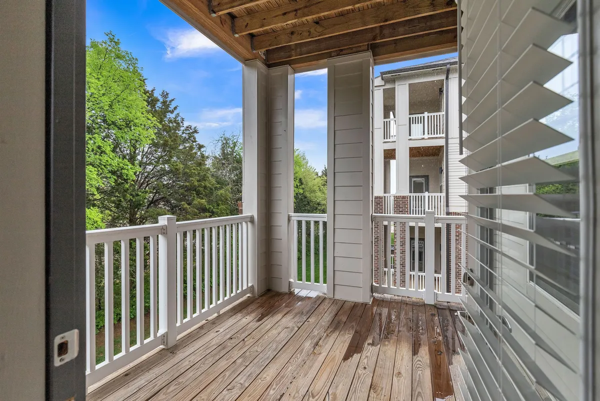 A tranquil wooden deck surrounded by green trees and shuttered windows, perfect for relaxing with a pet after a day outside. The setting suggests a seamless connection between indoor comfort and outdoor exploration.