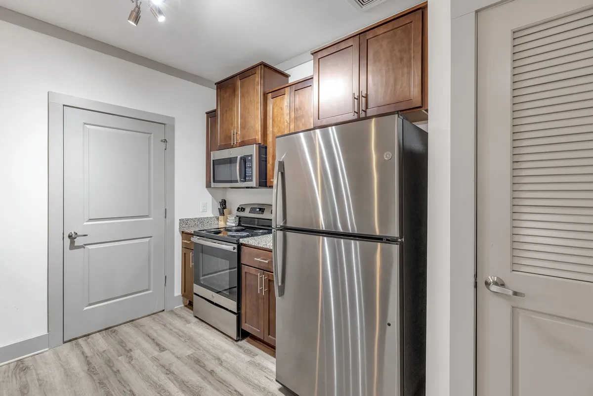 A contemporary kitchen with sleek stainless steel appliances, a spacious granite countertop, and wooden cabinetry. The setup is ideal for culinary creativity and hosting dinner parties or casual gatherings.