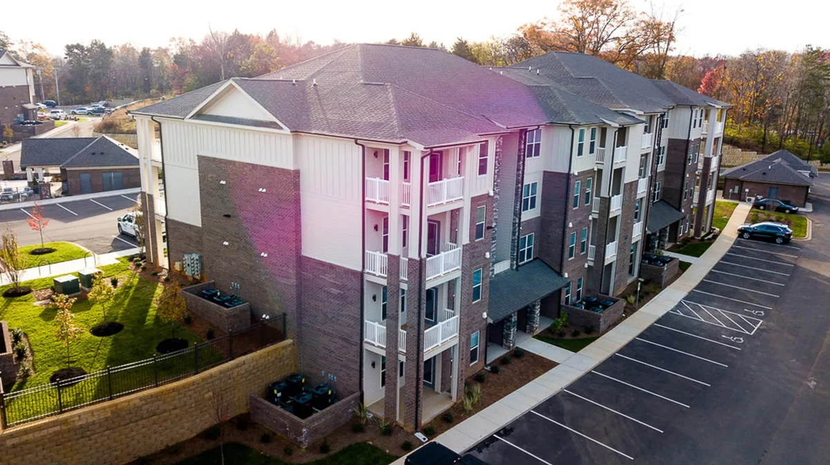 This image showcases the exterior of The Overlook, highlighting its modern architecture, landscaped surroundings, and inviting balconies. The scene conveys a sense of arrival, connection to the neighborhood, and the welcoming ambiance of the property.